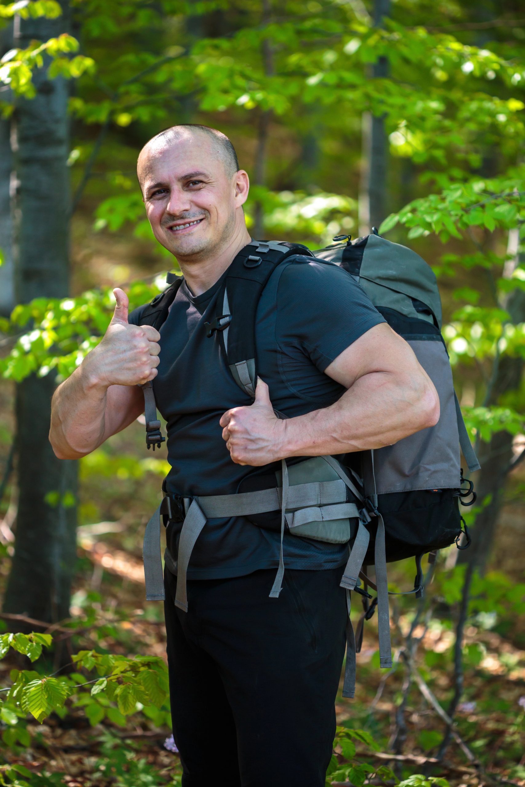 Photo of a male hiker in a forest giving a thumbs-up.